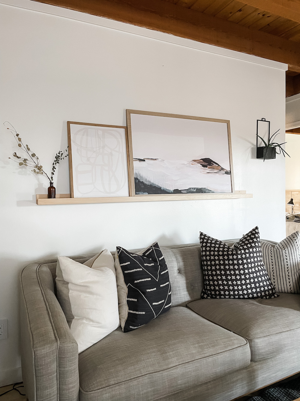 living room with gray couch and wood photo ledge with artwork