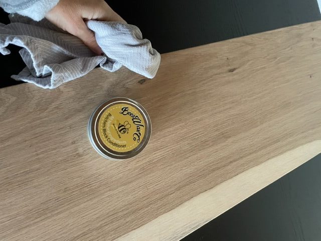 Woman, applying wood wax with a rag to a piece of white oak shelf