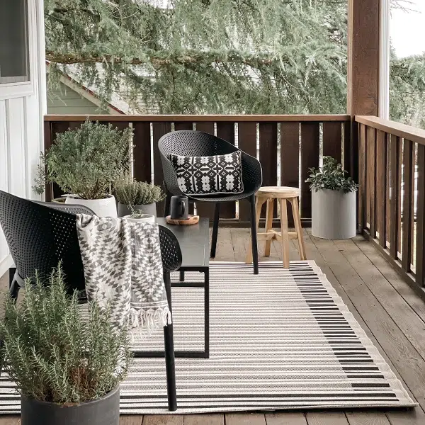 modern outdoor living room with rug, table, and chairs
