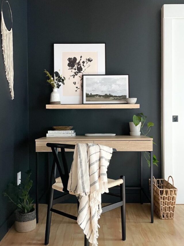 small office with desk, chair and artwork and black wall