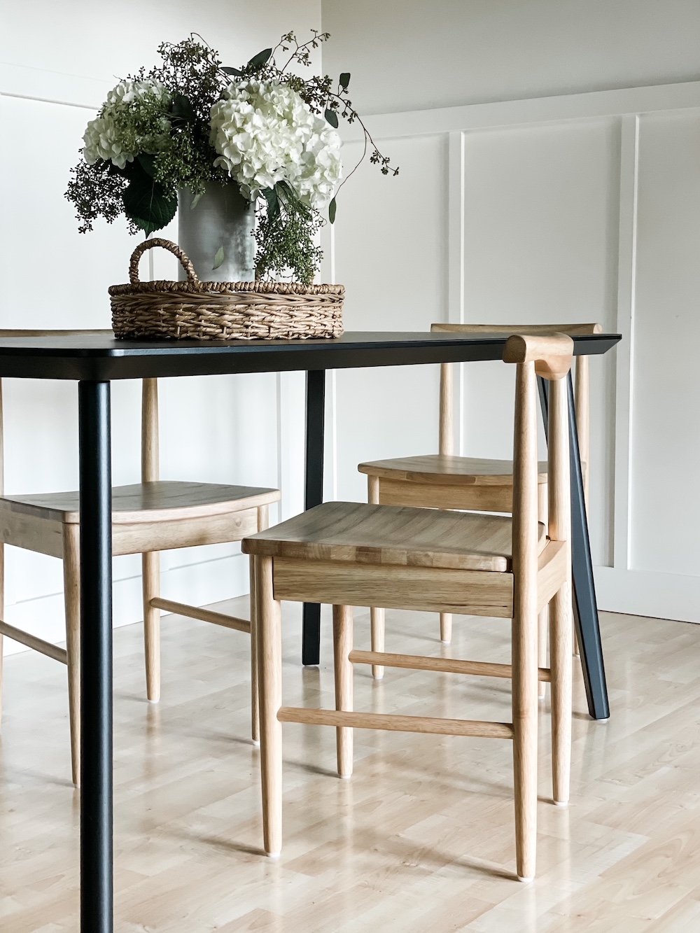black dining room table with mix of light wood chairs and flooring