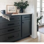 black kitchen cabinets painted with sherwin williams iron ore and white subway tile with decor including vase, artwork, and coffee mug
