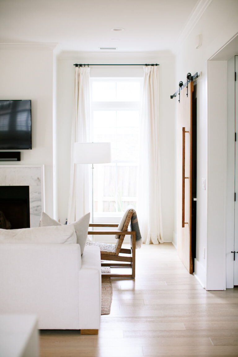 neutral living room with couch, chair, and curtains