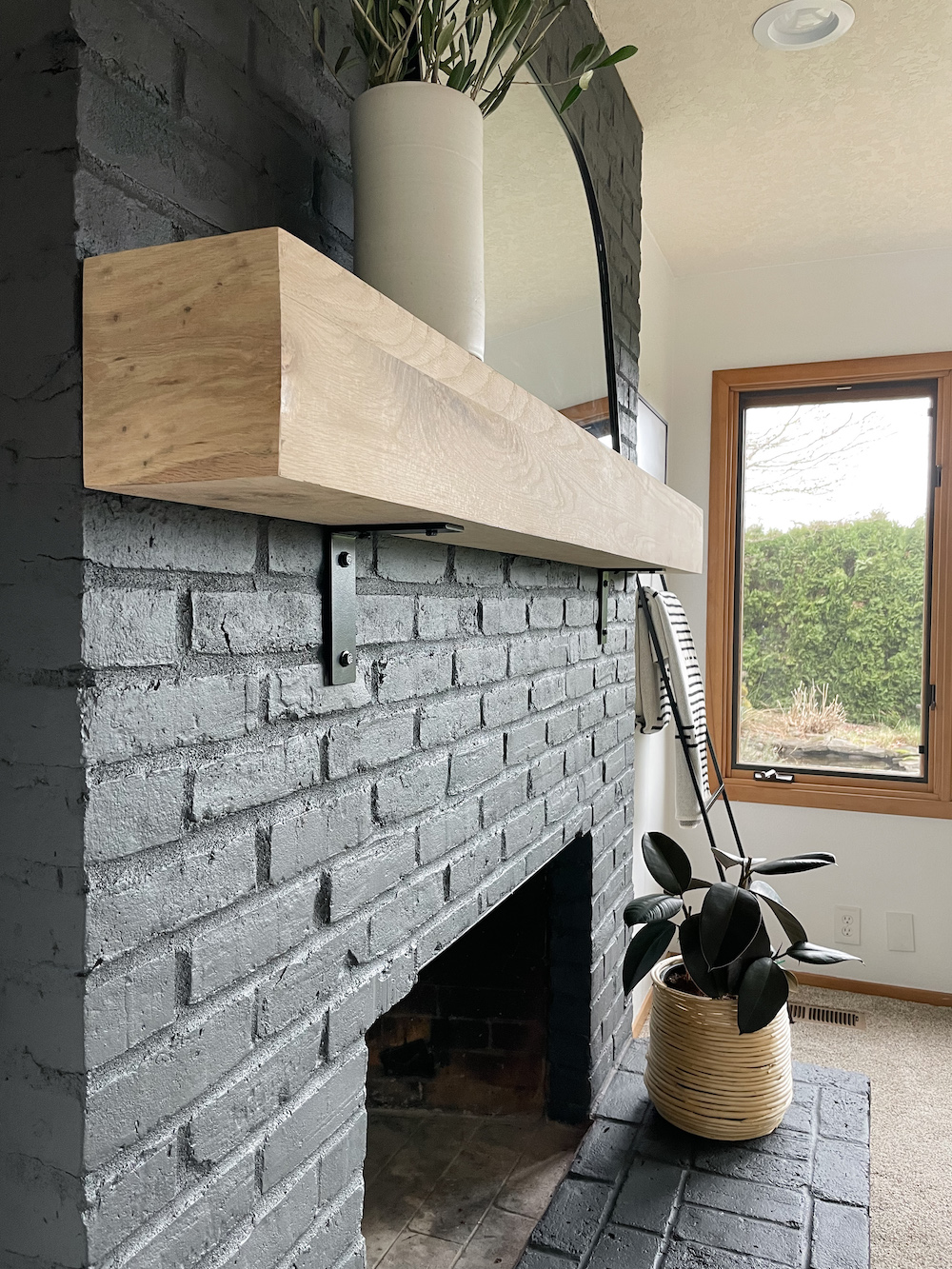 black brick fireplace with white oak mantel