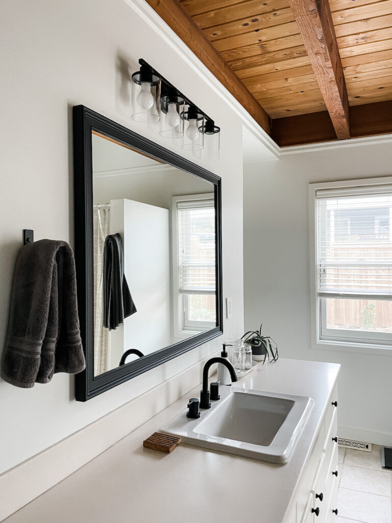 white bathroom with painted black mirror frame and black fixtures