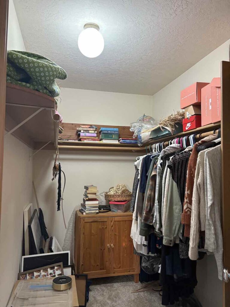 outdated messy closet with piles of books, boxes, artwork, and harsh lighting