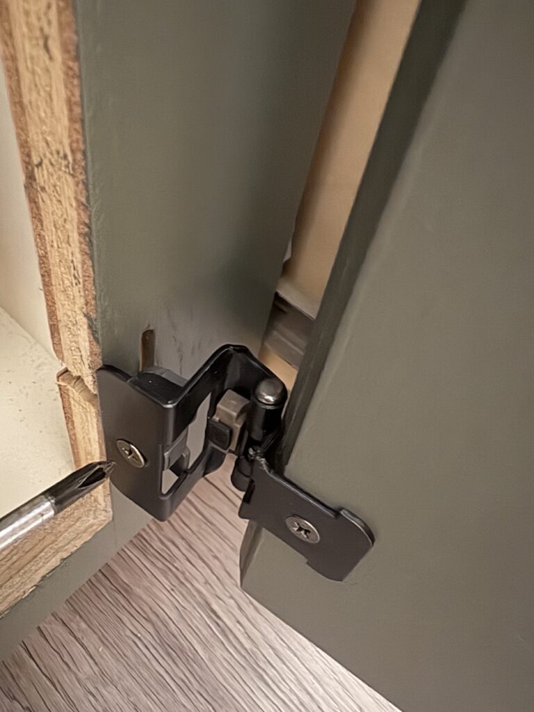 demountable black hinges on green bathroom cabinet