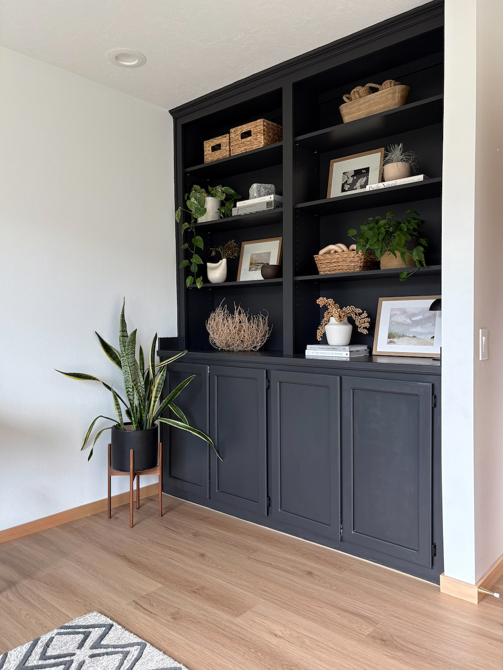 Office with painted black built in cabinets, shelf decor, and LVP natural look wood flooring