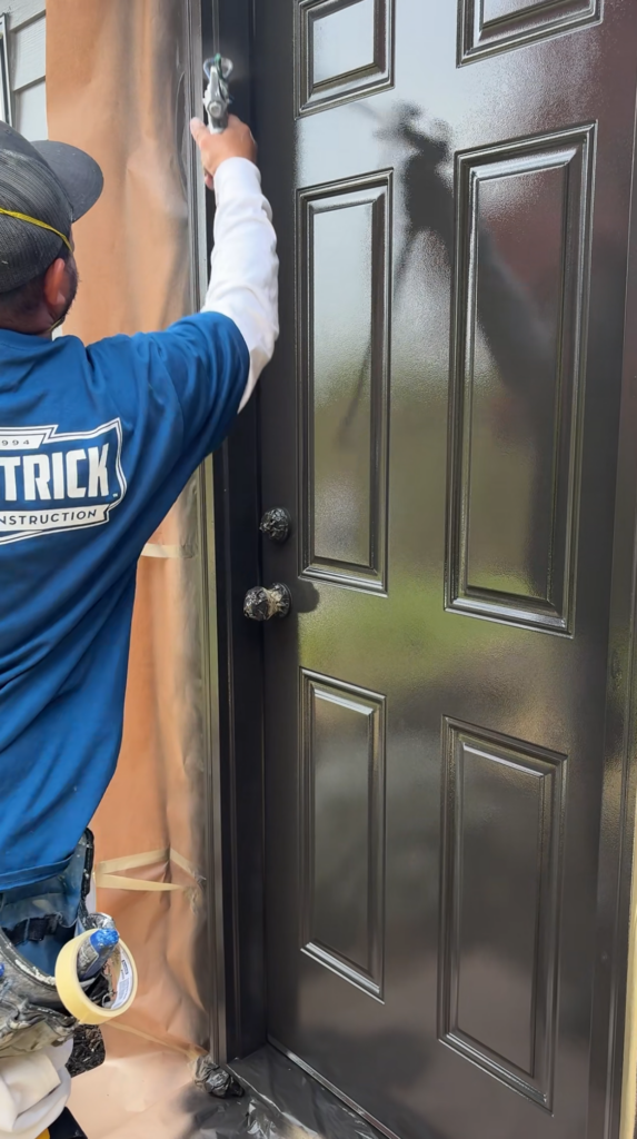 man painting an exterior house door a dark black color