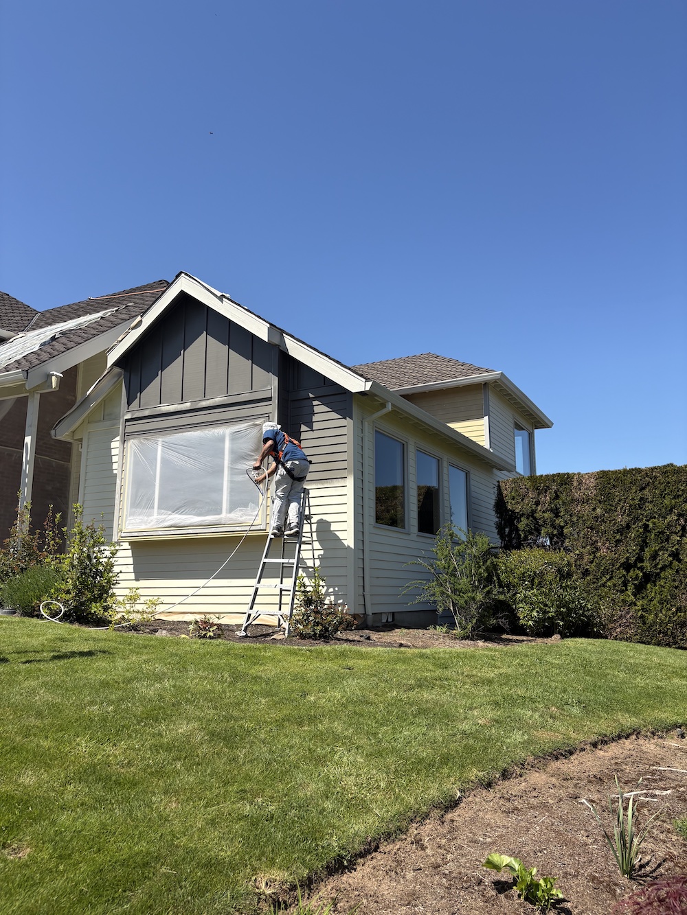 cream colored house being painted dark gray
