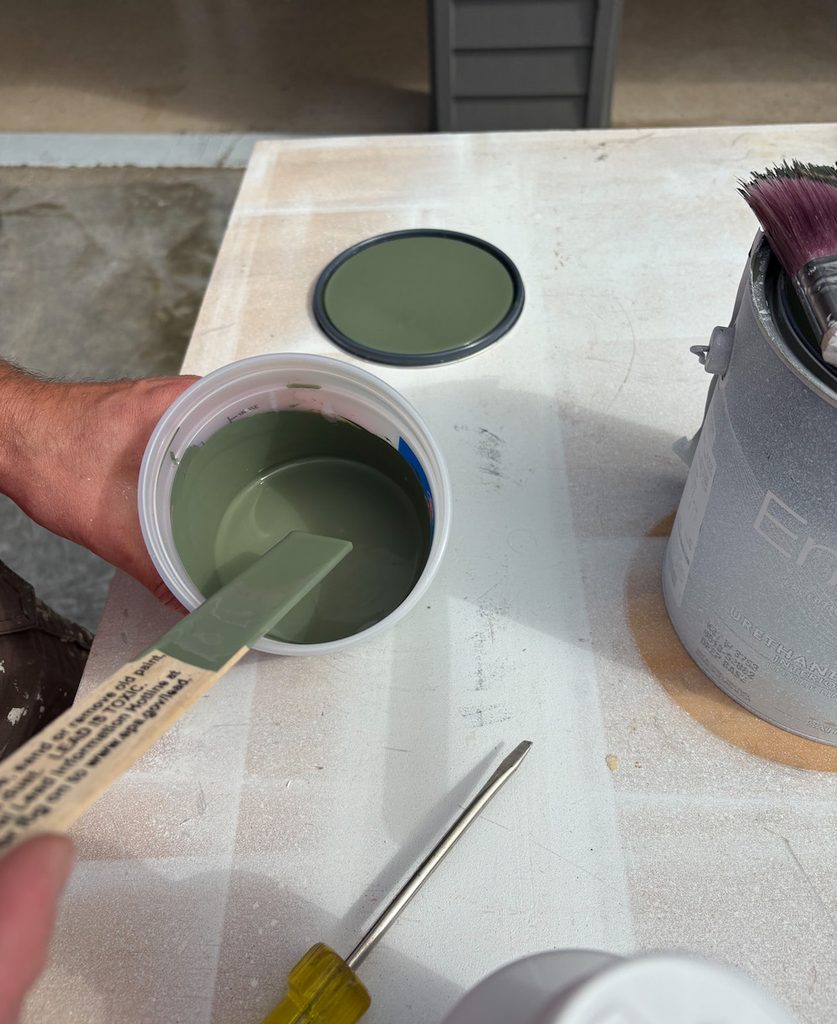 man holding cup of sherwin williams rosemary green paint